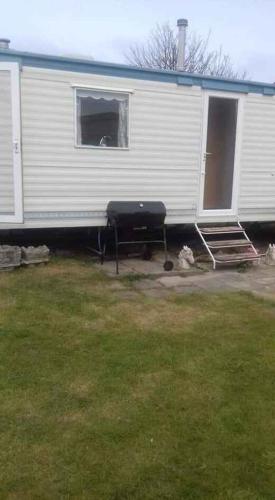 een witte trailer met een raam in een tuin bij Sandgate caravan park 2023 in Hemsby