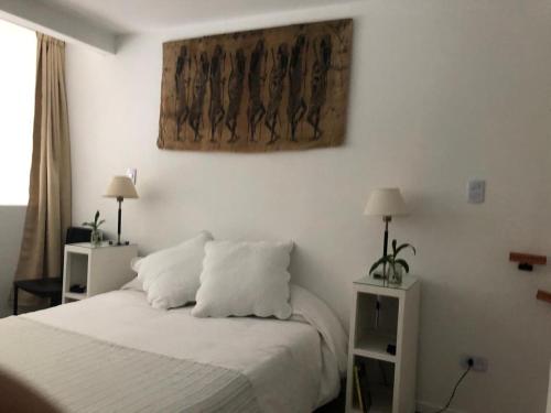 1 dormitorio con 1 cama con sábanas blancas y una pintura en la pared en Departamento nuevo a 4 cuadras de Palermo y 3 de Movistar Arena en Buenos Aires