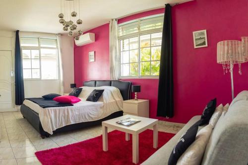 a bedroom with a bed and a pink wall at La Villa Mussanda avec piscine in Baie-Mahault