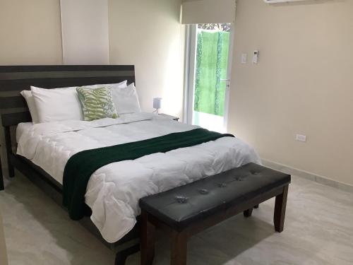 a bed with a green and white blanket and a bench at Minutes away from Mangel Halto Beach in Savaneta