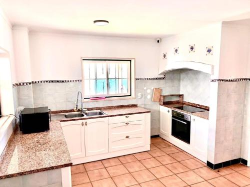 a kitchen with white cabinets and a sink and a window at Carcavelos Summer Beach in Carcavelos