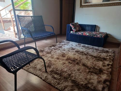 a living room with two chairs and a rug at Pousada Castro in Aparecida