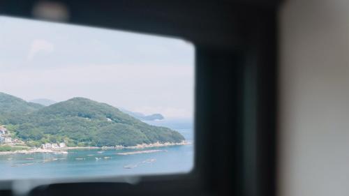 a view of the ocean from a window at Geoje Mongdol Beach H Avenue Hotel in Geoje 