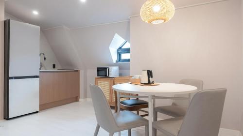 a kitchen with a table and chairs and a refrigerator at Geoje Mongdol Beach H Avenue Hotel in Geoje 