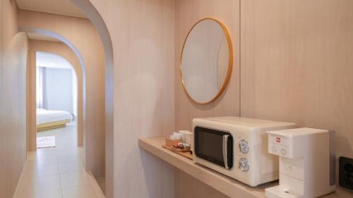 a room with a microwave and a mirror on a counter at Geoje Mongdol Beach H Avenue Hotel in Geoje 