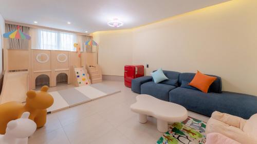 a living room with a blue couch and a play area at Geoje Mongdol Beach H Avenue Hotel in Geoje 