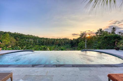 a swimming pool with a sunset in the background at Beten Juwet in Nusa Penida