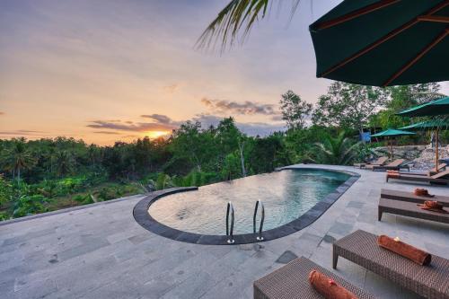 a swimming pool with a sunset in the background at Beten Juwet in Nusa Penida