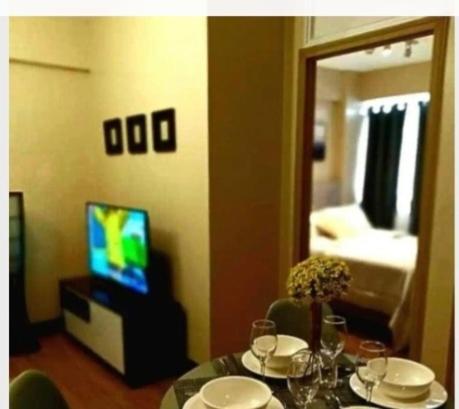 a dining room with a table and a television and a room at The Lancris Residences, 2 Bedrooms, 1 Bathroom, Livingroom & Kitchen Pool is free! in Manila