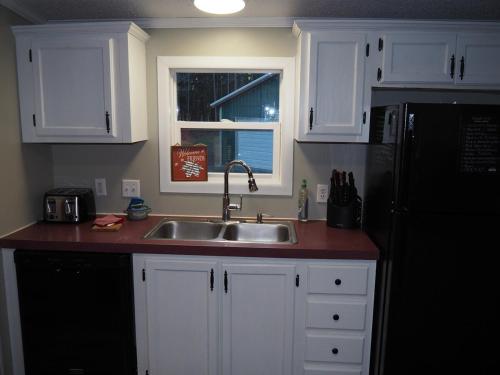 a kitchen with white cabinets and a sink and a window at The Green Lake Getaway - Shared Lake Access! in Interlochen