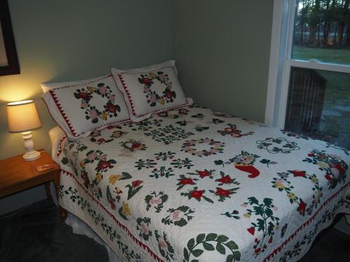 a bed with a flowered blanket and pillows on it at The Green Lake Getaway - Shared Lake Access! in Interlochen
