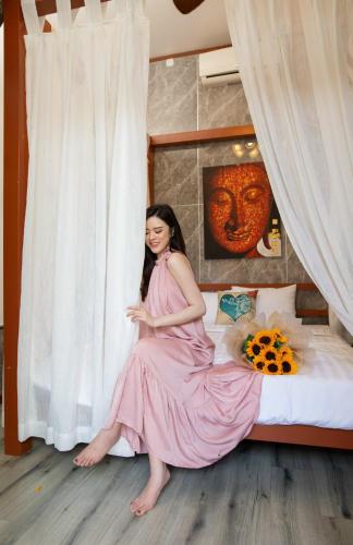 a woman in a pink dress sitting on a bed at HELLO VILLA & SPA in Hue