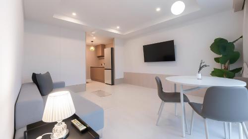 a living room with a table and chairs and a tv at Geoje Mongdol Beach H Avenue Hotel in Geoje 