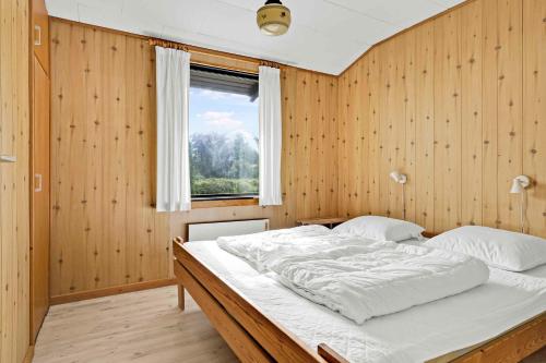 1 dormitorio con 1 cama grande y pared de madera en Beautiful Holiday Home From 1978, en Tranekær