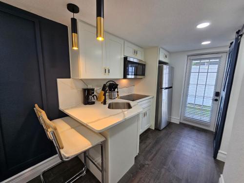 a kitchen with white cabinets and a sink and a refrigerator at The Hideaway DT Orlando Tiny Home w Free Parking in Orlando