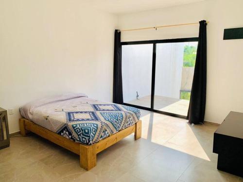 um quarto com uma cama e uma grande janela em Casa con alberca. em Tamazunchale