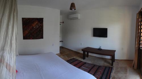 a bedroom with a bed and a table and a tv at Villa Albergaria in Flecheiras