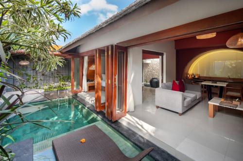 an indoor pool in a villa with a living room at Seminyak Sanctuary Villa by Ini Vie Hospitality in Legian