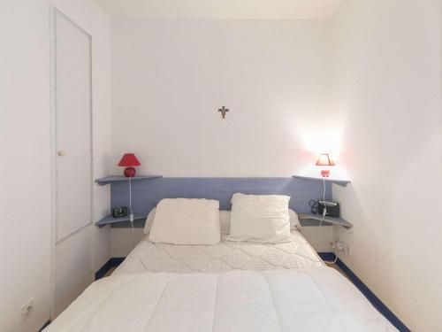 - un lit blanc dans une chambre avec une croix sur le mur dans l'établissement Appartement cosy à Cauterets - 4 pers, jardin, parking, proche centre et thermes. - FR-1-401-265, à Cauterets