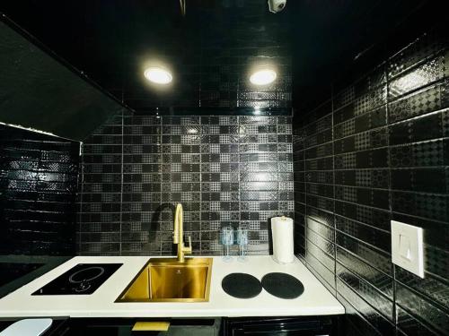アグアディヤにあるPasavento - Modern Tiny Suiteの黒いタイル張りの壁、洗面台付きのバスルーム