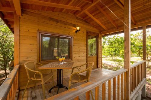 a porch of a log cabin with a table and chairs at Secret Garden Hotel & Bungalows in Cıralı