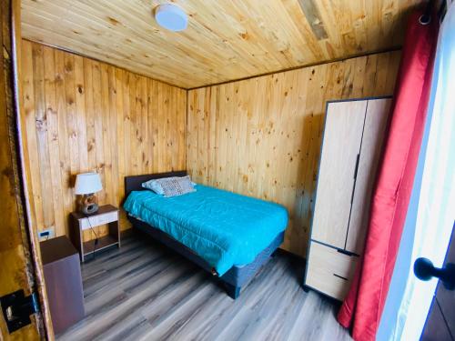 um quarto com uma cama num chalé de madeira em Cabañas EMC em Los Vilos