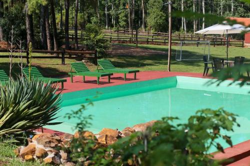 una piscina con 2 bancos verdes junto a un parque en Estancia La Paulina!!! 1 hora de las Cataratas!!! en Eldorado