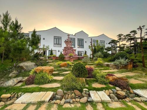 a garden in front of a large white house at TRANG Homestay in Bao Loc