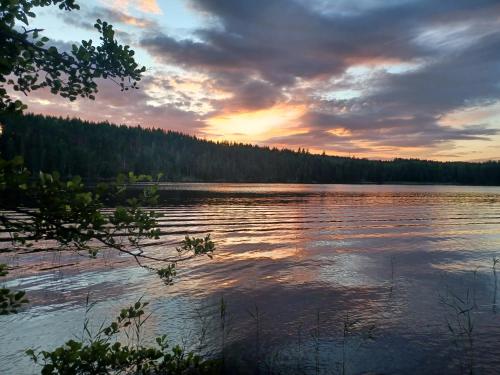 einen Sonnenuntergang über einem See mit Bäumen im Hintergrund in der Unterkunft Ekebol kvarn 