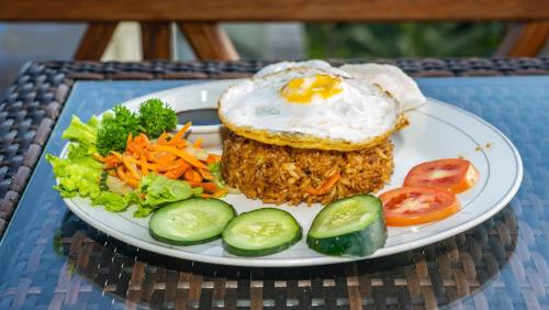 a plate of food with a fried egg and vegetables at Anja Villas Ubud in Tegalalang