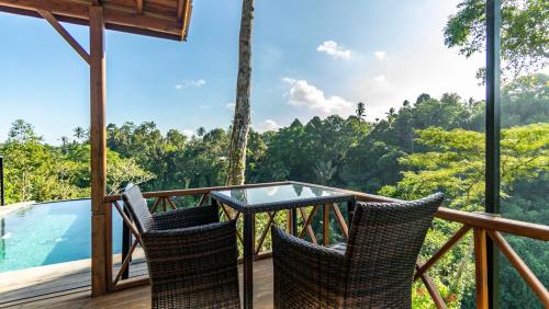 a balcony with a glass table and chairs on a deck at Anja Villas Ubud in Tegalalang