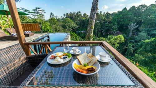 a table with a plate of food on a balcony at Anja Villas Ubud in Tegalalang