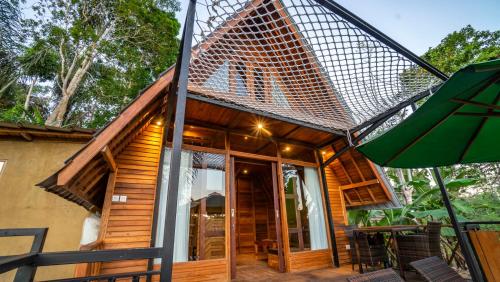 a wooden house with a mesh roof and an umbrella at Anja Villas Ubud in Tegalalang