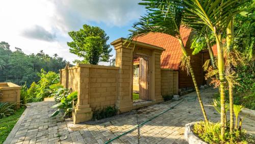 a brick house with a palm tree in front of it at Anja Villas Ubud in Tegalalang