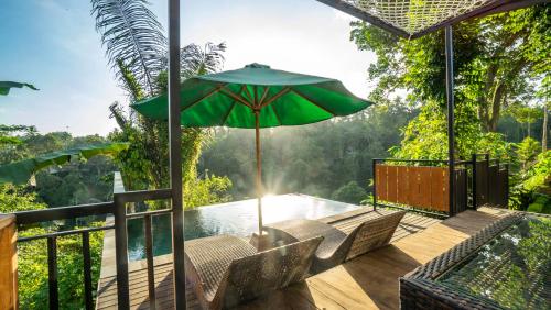 a deck with chairs and an umbrella and a pool at Anja Villas Ubud in Tegalalang