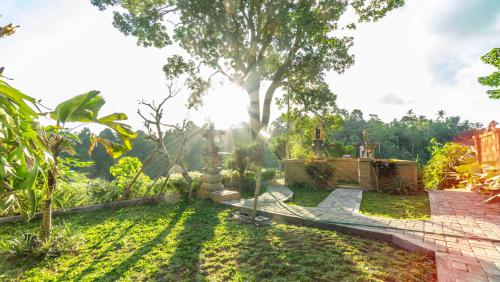 a garden with a tree in the background at Anja Villas Ubud in Tegalalang