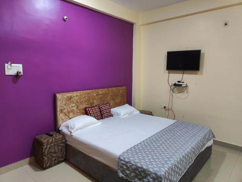 a bedroom with a purple wall and a bed at Om Paradise in Ujjain