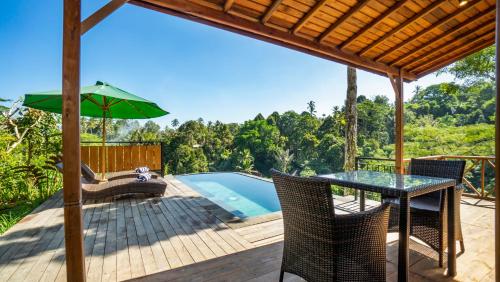 a patio with a table and chairs and a pool at Anja Villas Ubud in Tegalalang