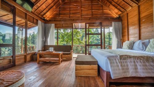 a bedroom with a bed and a table and windows at Anja Villas Ubud in Tegalalang