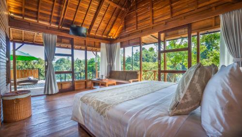 a bedroom with a bed in a room with windows at Anja Villas Ubud in Tegalalang