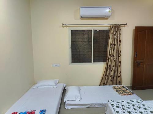 two beds in a room with a window at Om Paradise in Ujjain
