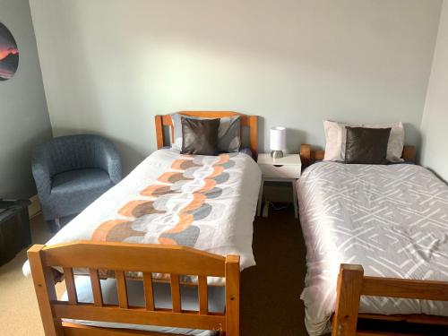 1 dormitorio con 1 cama, 1 silla, 1 cama y escritorio en RL Two-Bedroom Apartment, en Palmerston North