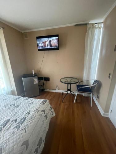 - une chambre avec un lit, une table et une télévision dans l'établissement Hospedaje el Mirador, à Puerto Montt