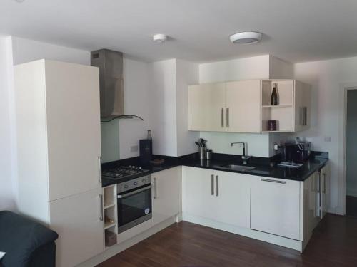 a kitchen with white cabinets and a sink and a stove at Double Room with Shared Bathroom in London