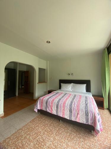 a bedroom with a bed with a pink and white comforter at The Sandy House Khaolak in Khao Lak