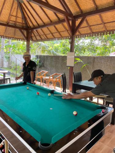 two men playing a game of pool at a pool table at Red island villas in Banyuwangi