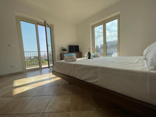 a bedroom with a large bed and large windows at Maison de Cheeramie - Tourist Apartments Tra Mare e Etna in Mascali