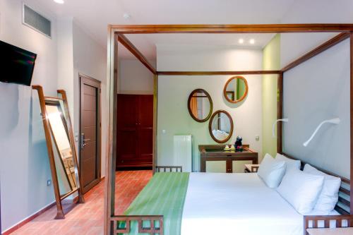 Un dormitorio con una cama blanca y un espejo. en Splanzia Boutique Hotel, en La Canea