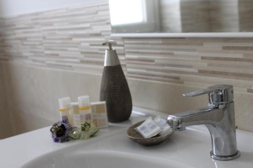 a bathroom sink with a faucet and some soap at Maison de Cheeramie - Tourist Apartments Tra Mare e Etna in Mascali