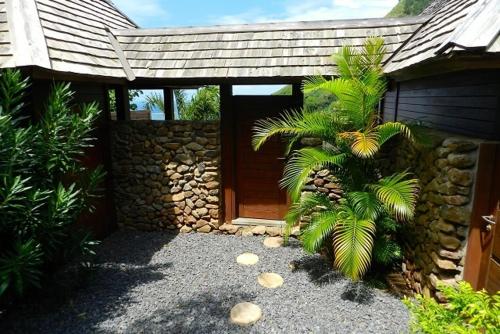 a house with a wooden door and some palm trees at Villa Rei in Papetoai